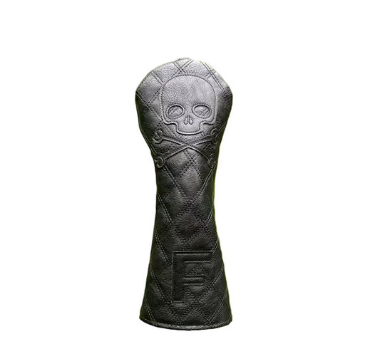 Black quilted golf club head cover with skull design on a blurred green grass background